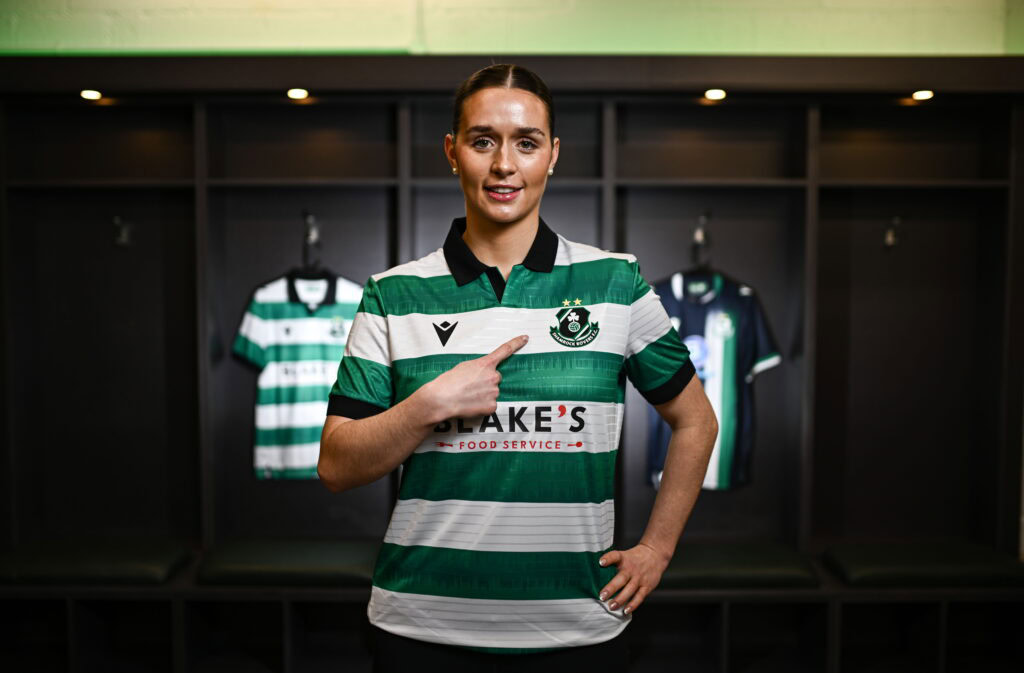 Shamrock Rovers female player in team jersey at locker room.