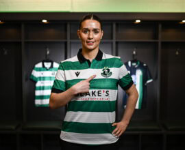 Shamrock Rovers female player in team jersey at locker room.